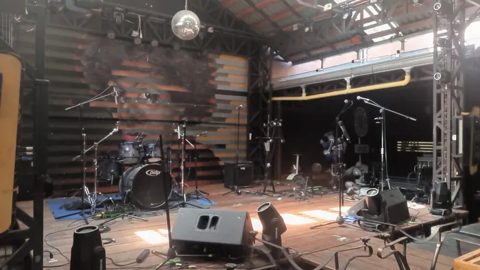 Red Macaw stage setup with drums, microphone stands and monitors
